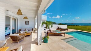 Un'area relax esterna moderna con piscina, sedie a sdraio e vista sull'oceano.