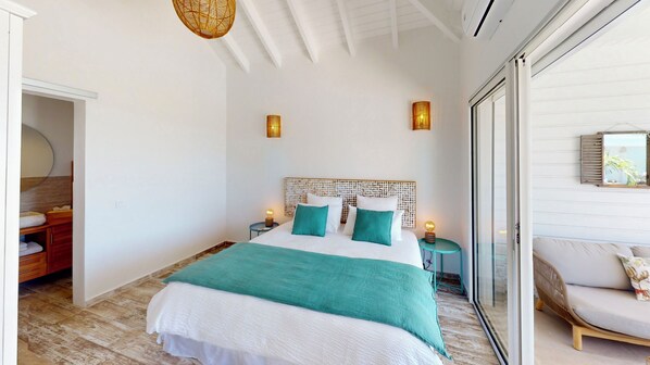 A bedroom with a large bed, two bedside lamps, a wooden headboard, and a view through a glass door. - ORIENT BAY - 6 bedrooms - Breathtaking ocean views - Sunseeker SXM (SAINT MARTIN)