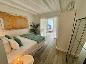 Une chambre à coucher avec un lit, une plante, une chaise, un bureau et une armoire.
