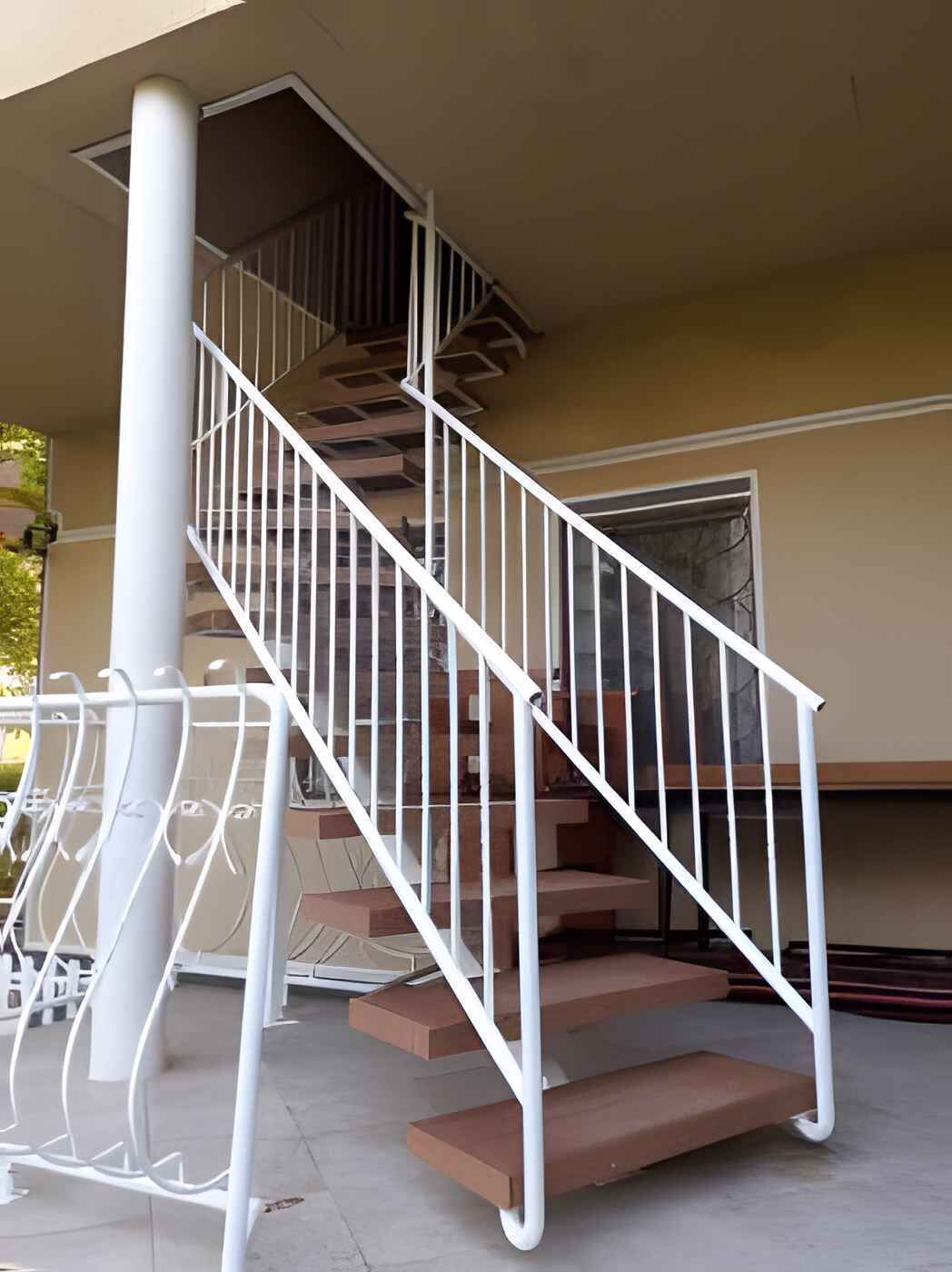 A staircase with white railings and brown steps leading to an upper floor.