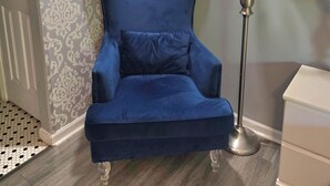 A blue armchair with a cushion, a floor lamp, a patterned wall, and a white cabinet. - Paul's Apartment - 55in TV, Wi-Fi, kitchenette (Helen)