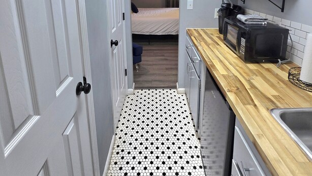 A compact kitchen with a tiled floor, a microwave, a sink, and a wooden countertop. - Paul's Apartment - 55in TV, Wi-Fi, kitchenette (Helen)