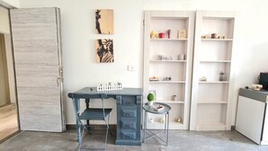 Quarto com escrivaninha, cadeira e estantes com diversos objetos.