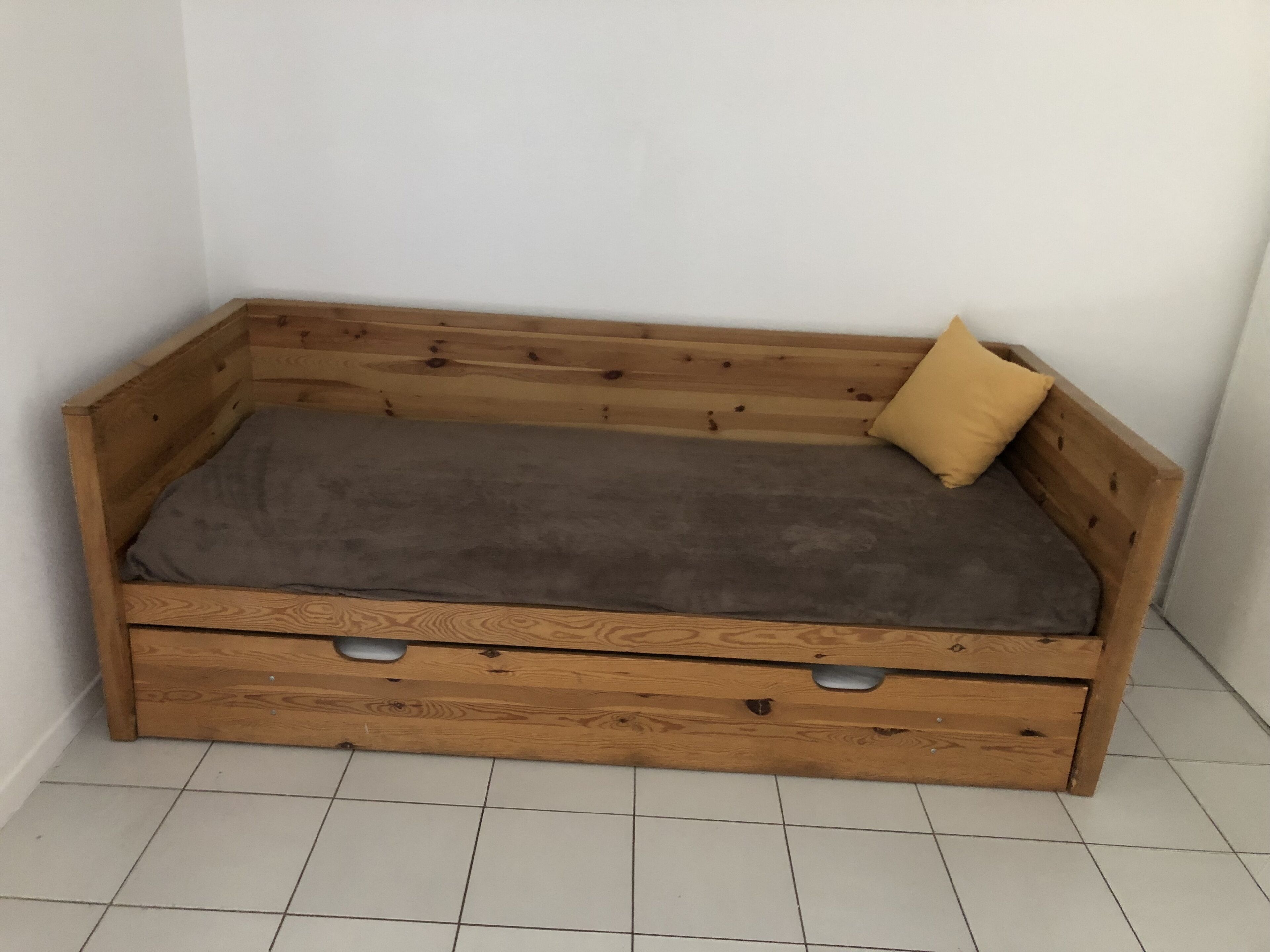 A wooden bench with a grey cushion and a single yellow pillow.