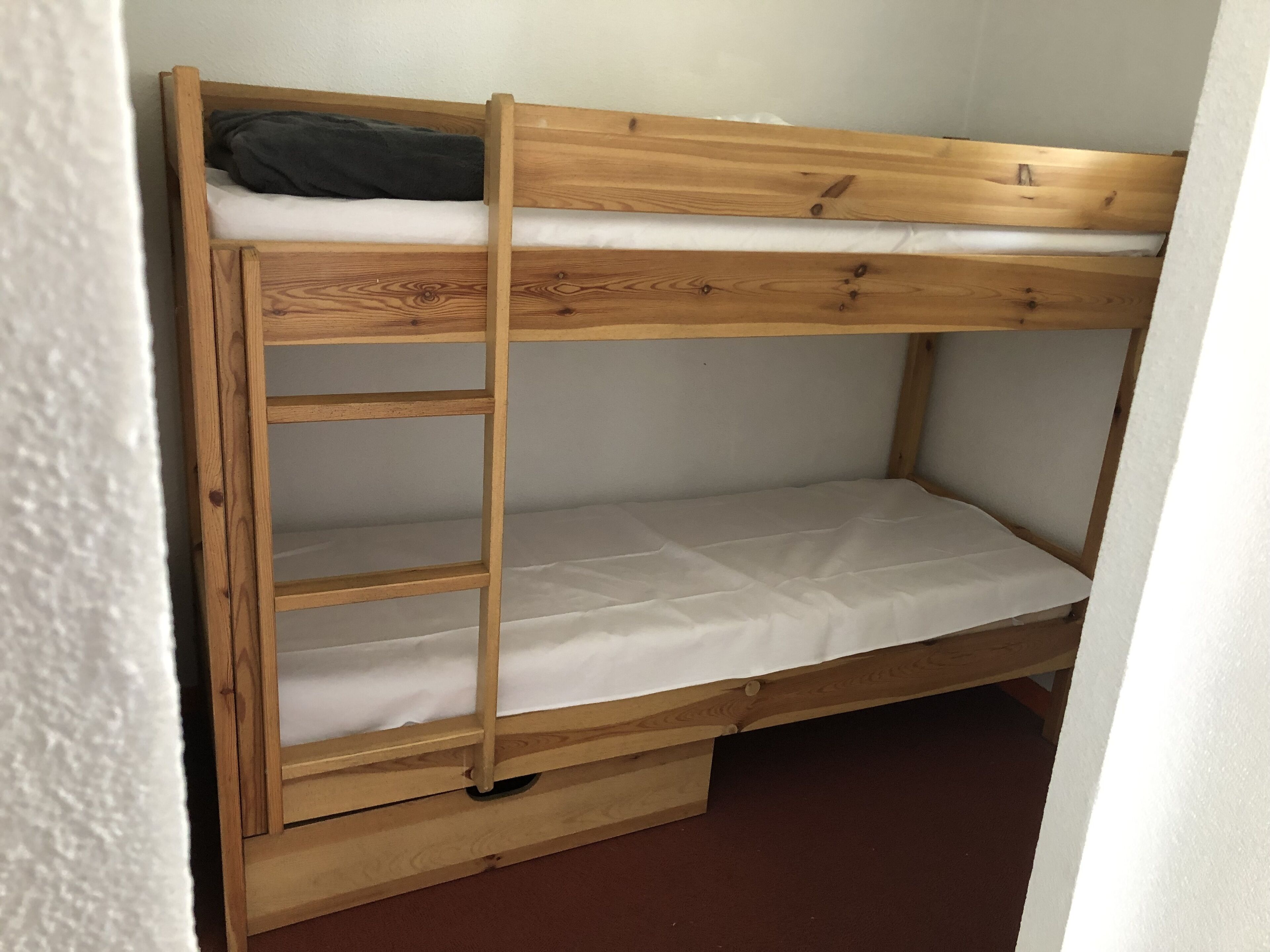 A bunk bed with a wooden frame and white bedding.