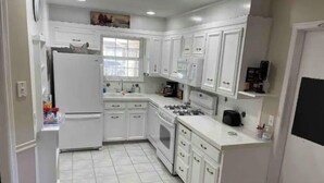 A kitchen with white cabinets, a refrigerator, a stove, and a sink. - The hunt club (Tulsa)