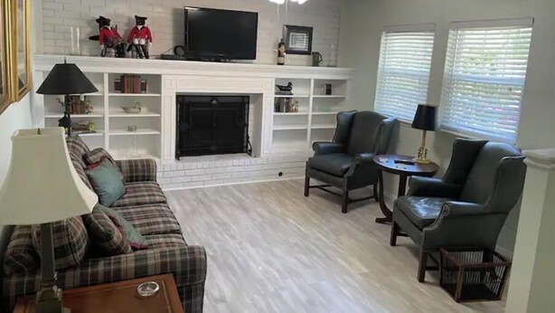 A living room with a fireplace, a television, and a ceiling fan. - The hunt club (Tulsa)