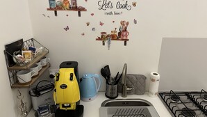 Et køkken med kaffemaskine, elkedel, brødrister og gaskogeplade.