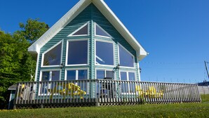 Une maison à deux étages, dotée d’un toit à pignon et d’une véranda entourée d’une clôture.