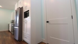 Una cocina moderna con armarios blancos, un refrigerador de acero inoxidable y un microondas.