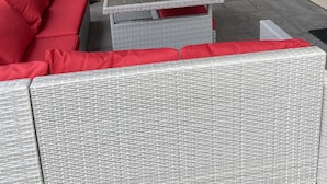 Un espacio al aire libre con mobiliario de mimbre y separadores de madera.