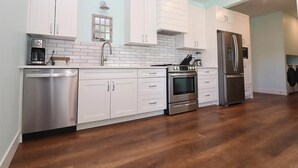 Una cocina moderna con armarios blancos, electrodomésticos de acero inoxidable y suelo de madera.