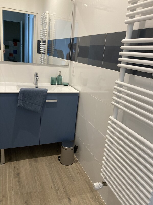 Casa de banho com lavatório, espelho e porta-toalhas.
