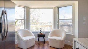 A modern kitchen with a large window, two white chairs, and a small table with a tray.