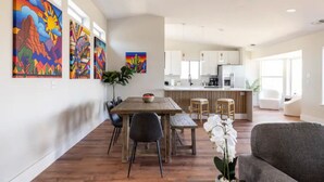 A modern kitchen with white cabinets, a central island, and a dining area with a wooden table and chairs.