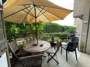 A patio with a round wooden table, four chairs, and a large umbrella. - Duplex at Siwar Resort, 1 bedroom, Wi-Fi, parking, near Rimal (ZOUK MOSBEH)