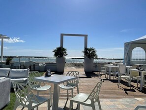 An outdoor patio with white furniture, potted plants, and a view of the sea. - The Vele Holiday House (three-room apartment—2 bedrooms—with a pool) (Comacchio)