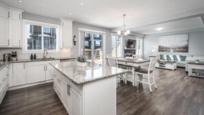 A modern kitchen with white cabinets, a granite countertop, and a large island. - Entire Executive Home, Walk to lake! (Chestermere)