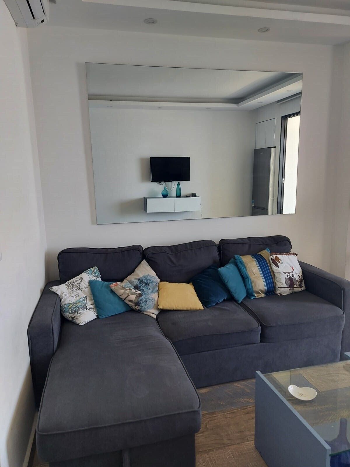 Una sala de estar moderna con un sofá modular, un televisor de pantalla plana y una mesa de centro de vidrio.
