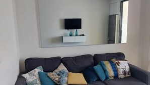 Ett modernt vardagsrum med en hörnsoffa, en platt-TV och ett soffbord i glas.