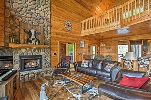 A log cabin interior with a stone fireplace, leather furniture, and a wooden ceiling. - Blue Ridge Luxury Cabin w/ Views, Movie Theater, EV Charger & Hot Tub (Morganton)
