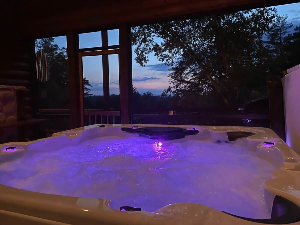 Un jacuzzi con vistas a árboles y al atardecer.