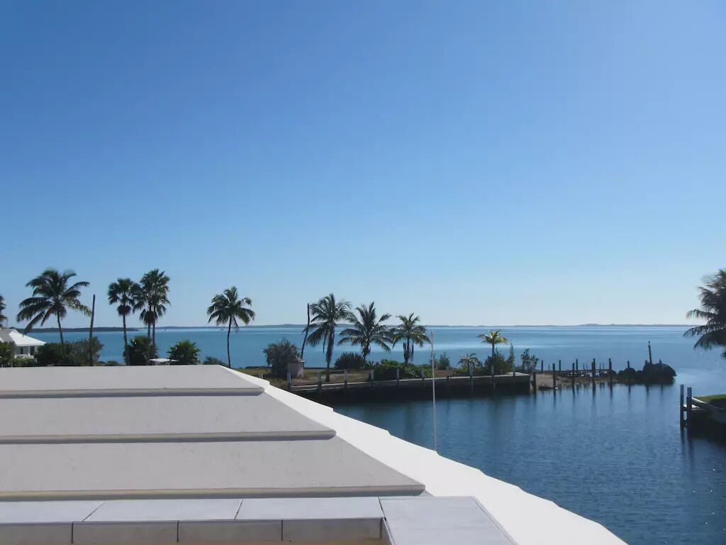 Zwembad van een resort met uitzicht op de oceaan en palmbomen.