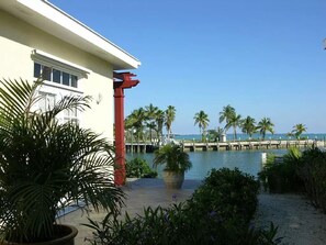A beachfront property with a white building, palm trees, and a pier extending into the water.