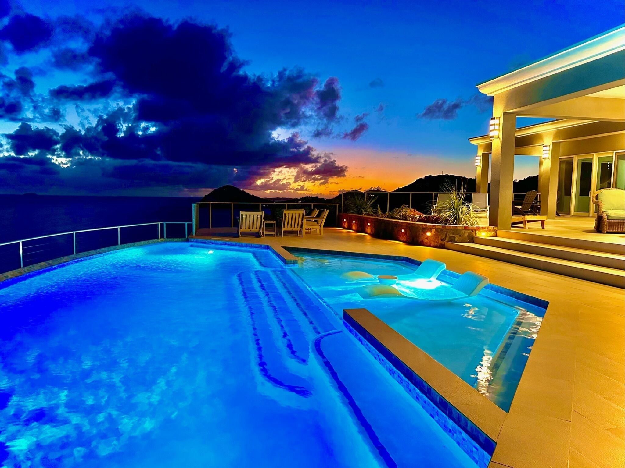 Una piscina con vista al océano y al atardecer.