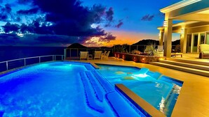 Una piscina con vista al océano y al atardecer.