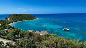 Un paisaje costero con una pequeña isla, aguas turquesas cristalinas y varios barcos.