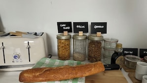 A kitchen counter with a loaf of bread, jars labeled with food items, and a toaster. - L'Orangerie du Château Loyd Pays de Caux (Les Hauts-de-Caux)