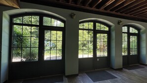 A room with large arched windows, a wooden ceiling, and a doormat on the floor. - L'Orangerie du Château Loyd Pays de Caux (Les Hauts-de-Caux)