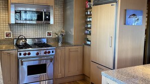 A modern kitchen with wooden cabinets, a stainless steel stove, and a built-in oven. - Mountain Cabin Rentals (Ward)