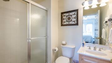 Une salle de bain avec une douche à parois de verre, des toilettes, un lavabo avec un meuble-vasque et un miroir avec éclairage.