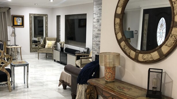 Un salón amplio con un espejo grande, un sofá, una mesa de centro y un televisor.
