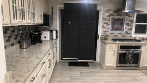Una cocina moderna con armarios blancos, un refrigerador negro, un microondas, una estufa y un salpicadero de azulejos.