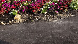 Un panneau indiquant l’entrée de Lighthouse Bay, situé près de Brooks, avec une bordure décorative et un parterre de fleurs devant.