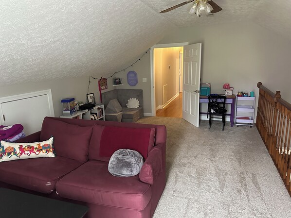 A cozy room with a red couch, a desk with a chair, a bookshelf, and a ceiling fan. - House for Graduation Weekend in Blacksburg, VA 5 minutes from campus! (Blacksburg)