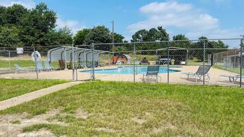 A fenced outdoor swimming pool area with lounge chairs and a covered pavilion.