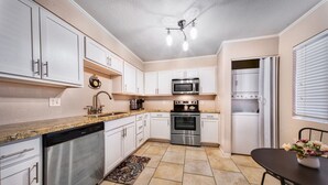 A modern kitchen with white cabinets, stainless steel appliances, and a granite countertop. - The Cactus Flower at McCormick Ranch (Scottsdale)