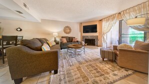 A living room with a sofa set, a coffee table, a fireplace, and a television. - The Cactus Flower at McCormick Ranch (Scottsdale)