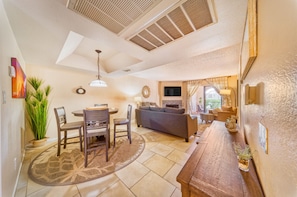 A spacious living room with a dining area, a sofa, and a TV.