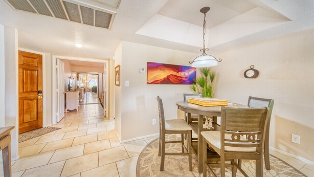 A dining area with a round table, chairs, a hanging light fixture, and a painting on the wall. - The Cactus Flower at McCormick Ranch (Scottsdale)
