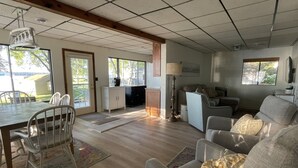 A spacious living room with a dining area, large windows, and a view of the outdoors. - Lake Frontage, swimming area, close to golf (Markesan)