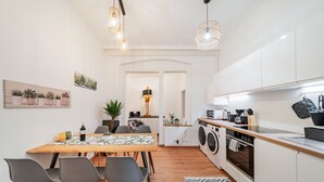 A modern kitchen with a dining area, including a table with chairs, a washing machine, and a microwave. - 3 Bedrooms - 75sqm - 15 Min. City Center (Vienna)