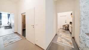 A spacious hallway with a bed, a shower, and a dining area. - 3 Bedrooms - 75sqm - 15 Min. City Center (Vienna)