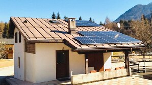 A small, single-story house with a sloped roof and solar panels. - Chalet Francesca (Pieve di Cadore)