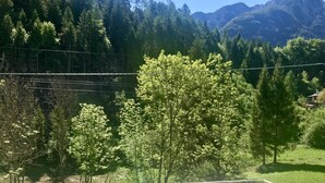 A checkered outdoor seating area with a view of a forested mountain range. - Chalet Francesca (Pieve di Cadore)
