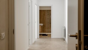 A hallway leading to a bathroom with wooden flooring and a white sink. - Chalet Francesca (Pieve di Cadore)